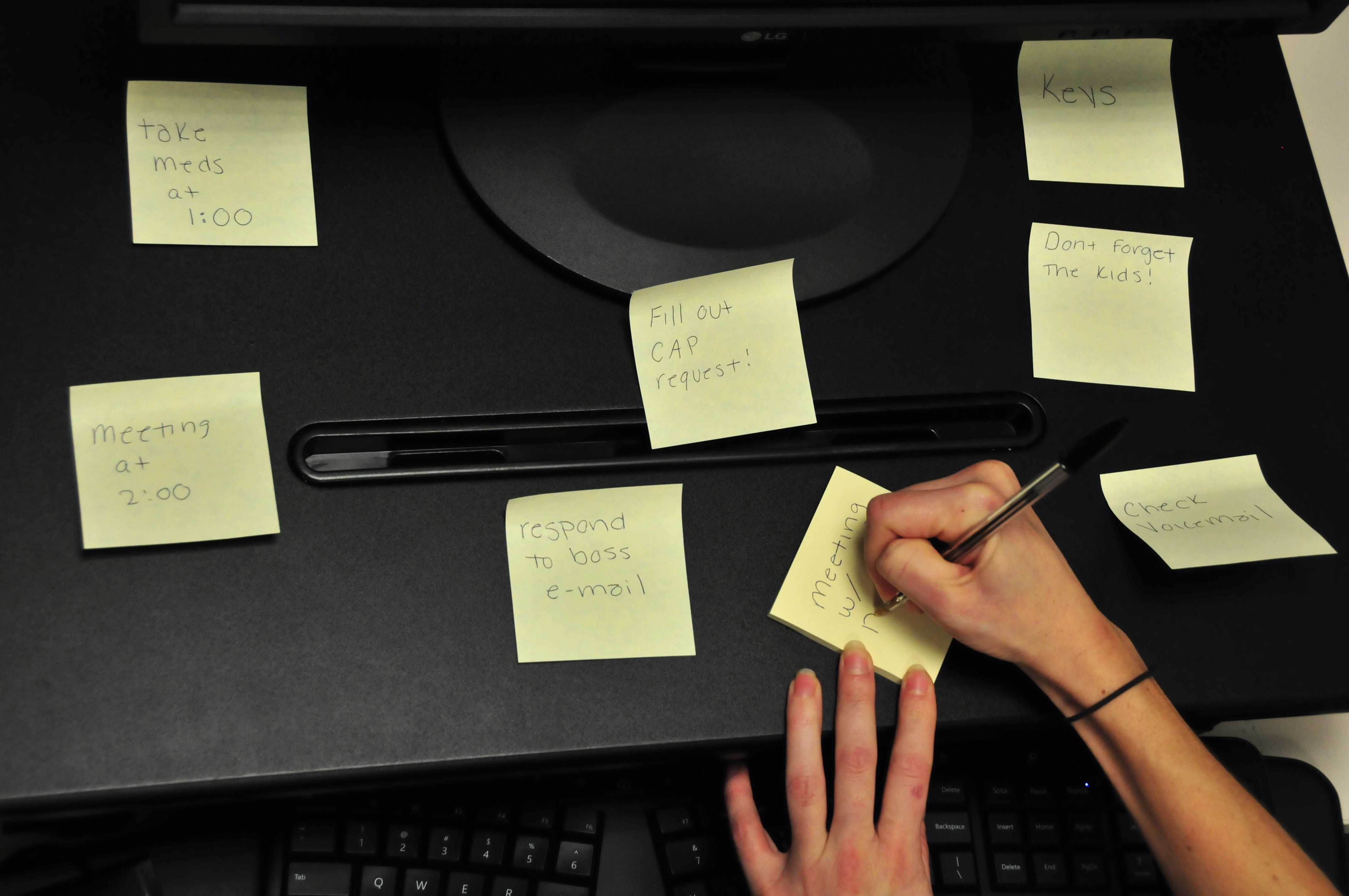 Person writing a series of sticky note reminders
